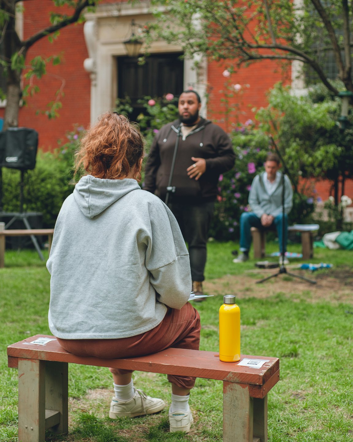 Un hombre se dirige a una audiencia al aire libre reunida en el césped.