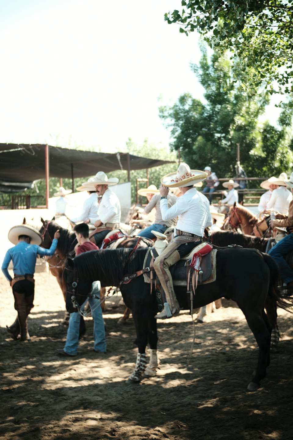 Hombres y niños con trajes de charro tradicionales se reúnen con caballos.